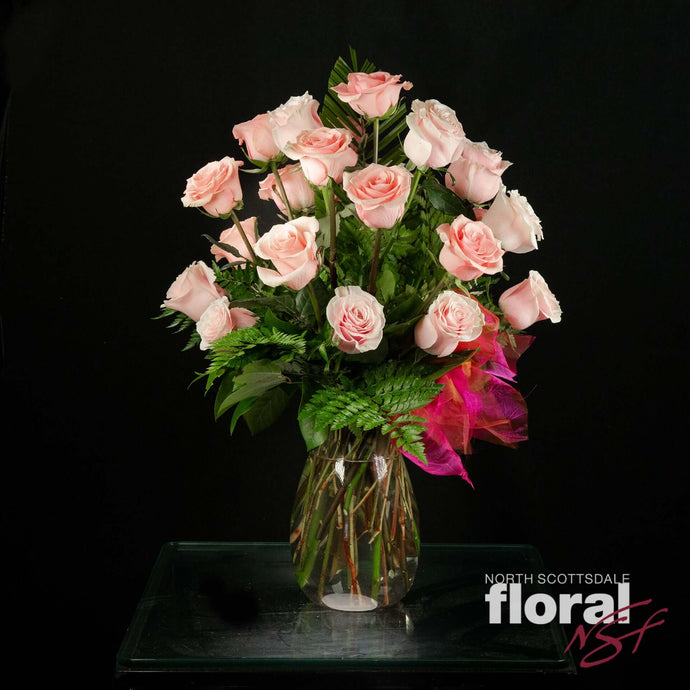 Two dozen pink Ecuadorian roses in a vase, accented with seasonal greenery. Perfect gift from a florist in Scottsdale.