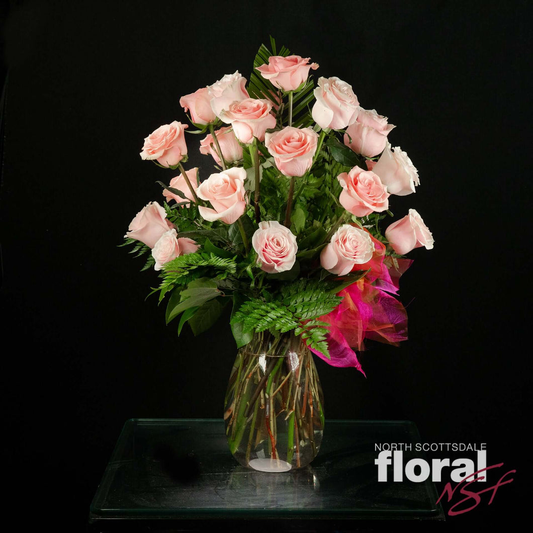 Two dozen pink Ecuadorian roses in a vase, accented with seasonal greenery. Perfect gift from a florist in Scottsdale.